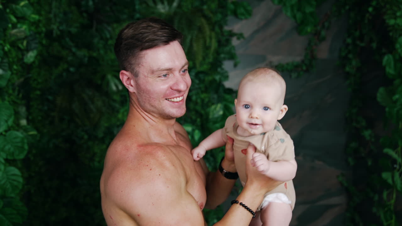 Loving dad kisses his cute little baby. Father tosses his son up and the kid is smiling happily.