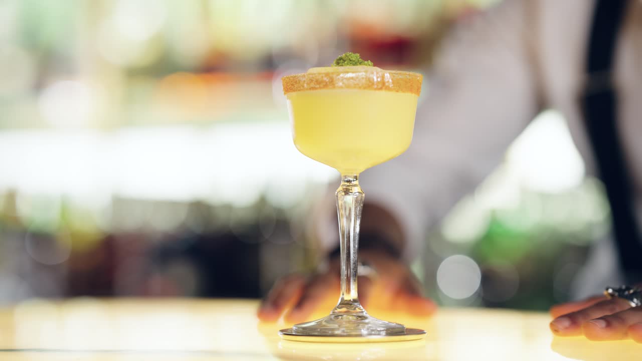 Barman Coloca un Cóctel Amarillo con el Borde Azucarado en una Barra de Bar