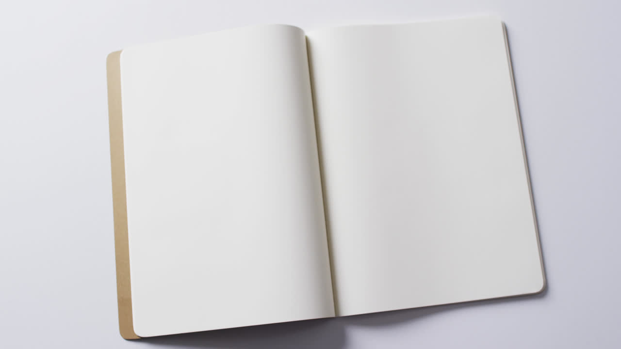 Close up of open blank book with copy space on white background in slow motion