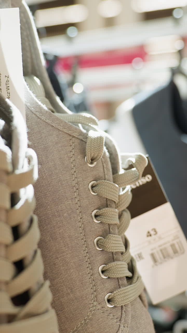 쇼핑몰의 랙에 매달린 신발의 클로즈업 뷰: 이 비디오는 현대적인 신발과 쇼핑 분위기를 보여주는 소매 환경에서 표시되는 다양한 스타일의 신발을 강조합니다.