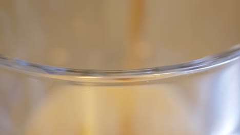 the lip of a large glass in focus as a dark fizzy diet soda is being poured to the the top