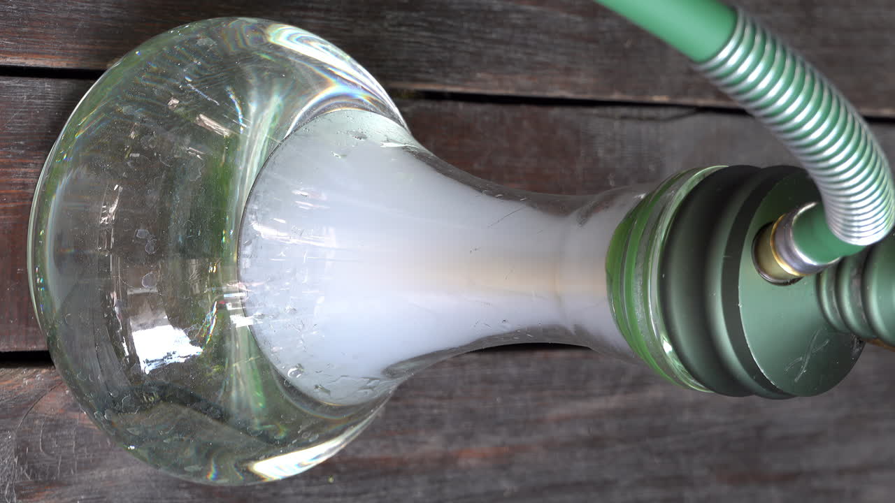 Close up of a transparent hookah on a wooden table. Vertical