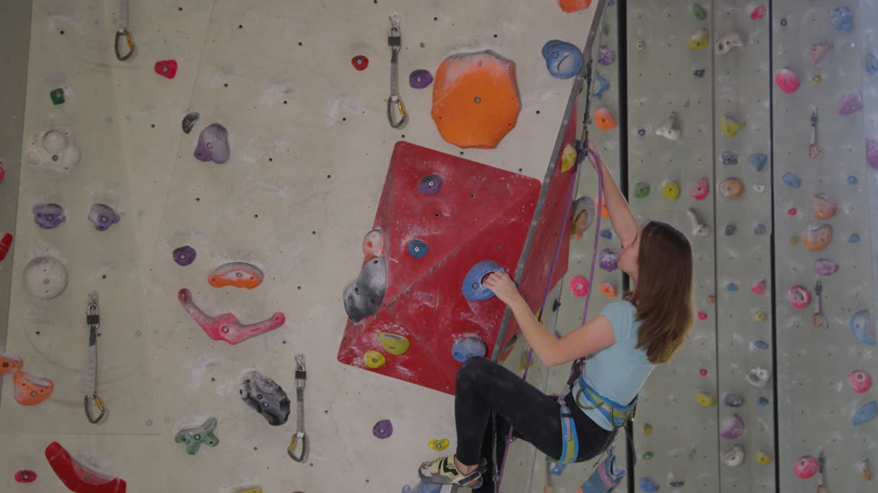 가까이에서: 집중된 십대가 실내에서 오르는 동안 어려운 경로를 오르고 있습니다.