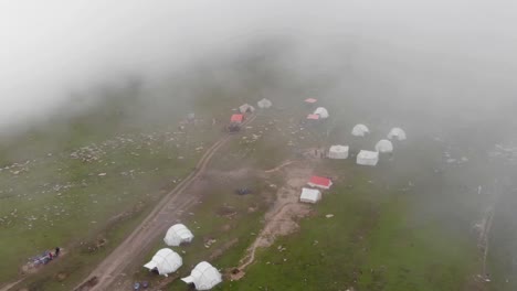 fog covered baboon valley in kashmir, pakistan, is seen from above, and several tents have been set up for the hikers to rest