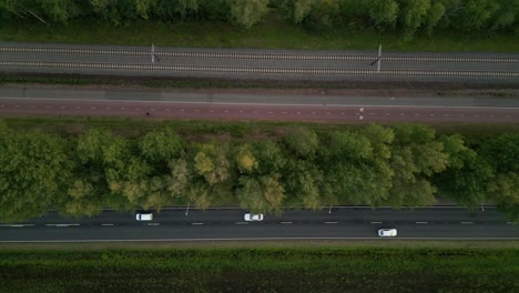 Diseño-De-Tráfico-Europeo:-Foto-Superior-De-Un-Ferrocarril,-Un-Carril-Bici-Y-Una-Carretera-Para-Coches-Que-Van-Uno-Al-Lado-Del-Otro-A-Través-De-Un-Paisaje-Verde