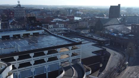 Overhead-aerial-view-above-city-multi-storey-car-park-quiet-British-urban-public-streets-at-sunrise