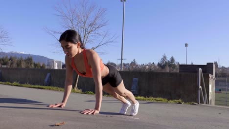 athletic young woman doing pushups outdoors. wide shot