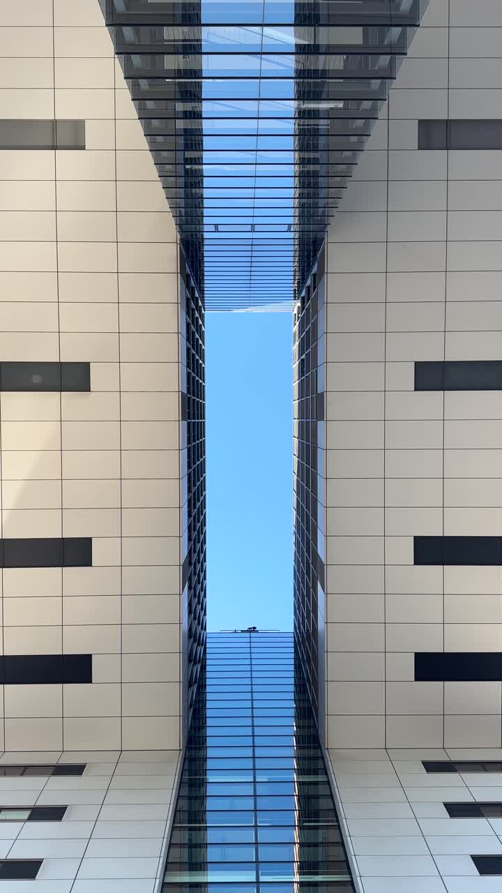 Impresionante vista vertical mirando hacia arriba entre las icónicas torres Kranhaus en Colonia, destacando las modernas líneas geométricas y el cielo azul enmarcado por las estructuras