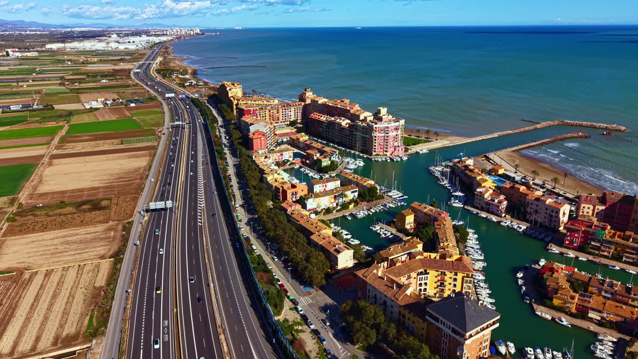 晴朗天空下的海岸景觀，一個船隻停泊的遊艇碼頭鄰近高速公路，背景是廣闊的田野。