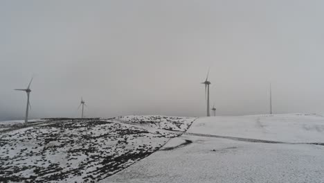 winter mountain countryside wind turbines on rural highlands aerial rising pan right view cold snowy valley weather