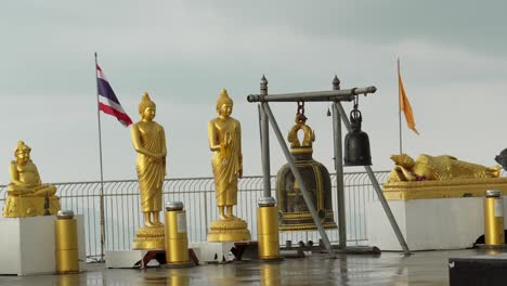 golden buddha statue at the big buddha phuket thailand wind and cloudy day buddhist flags