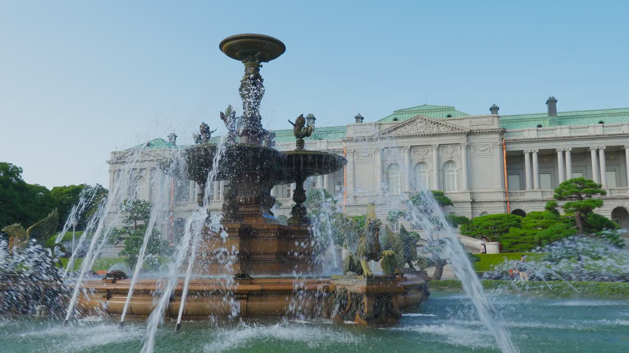 Una toma amplia de la elaborada fuente en el jardín con el elegante edificio principal de estilo occidental del Palacio de Akasaka al fondo.