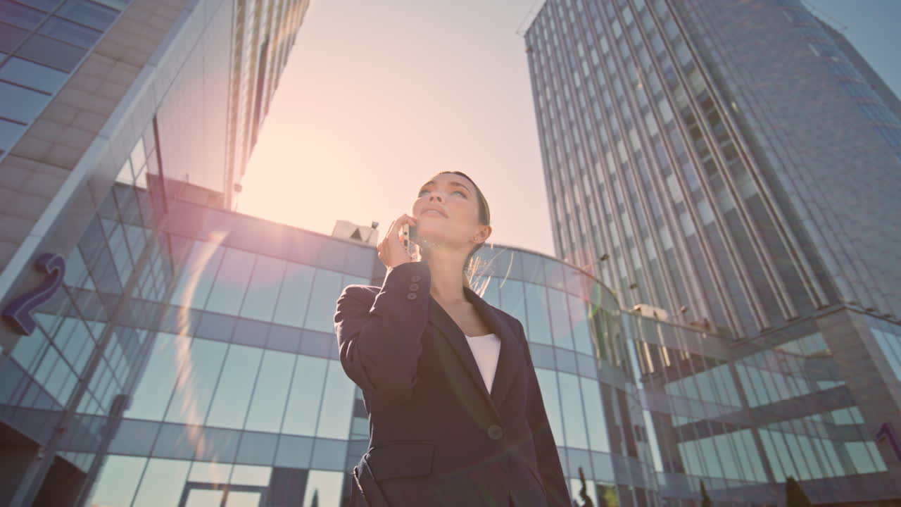 empleado de la compañía hablando por teléfono móvil a la luz del sol urbano. mujer de negocios llamando