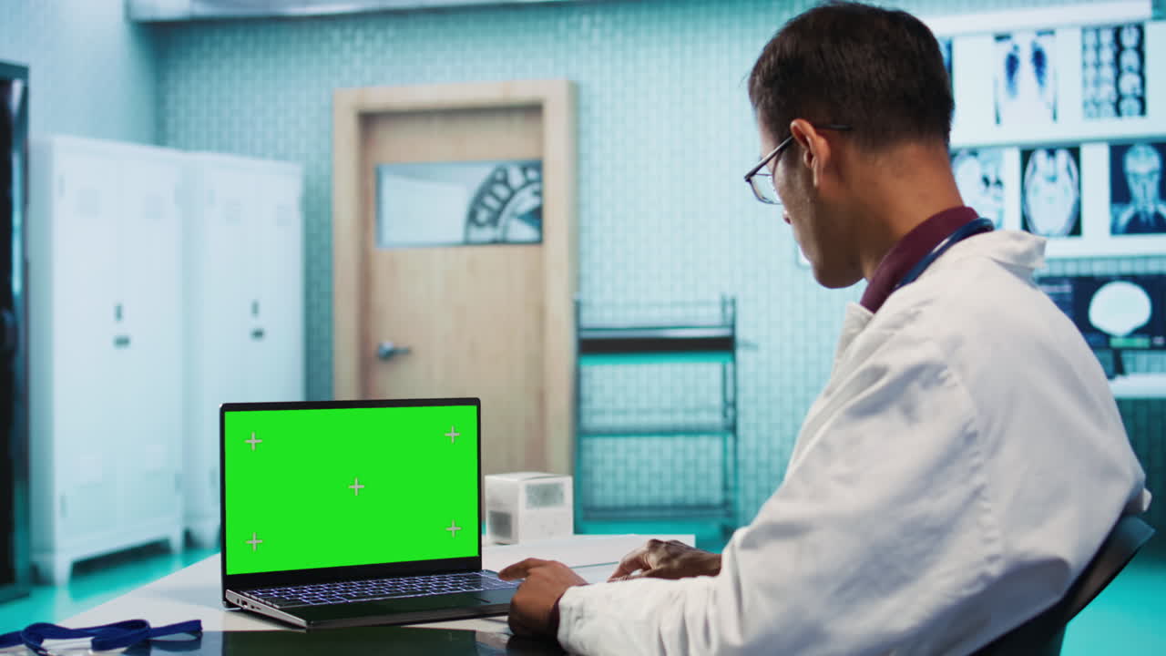 Doctor using laptop with green screen in clinic