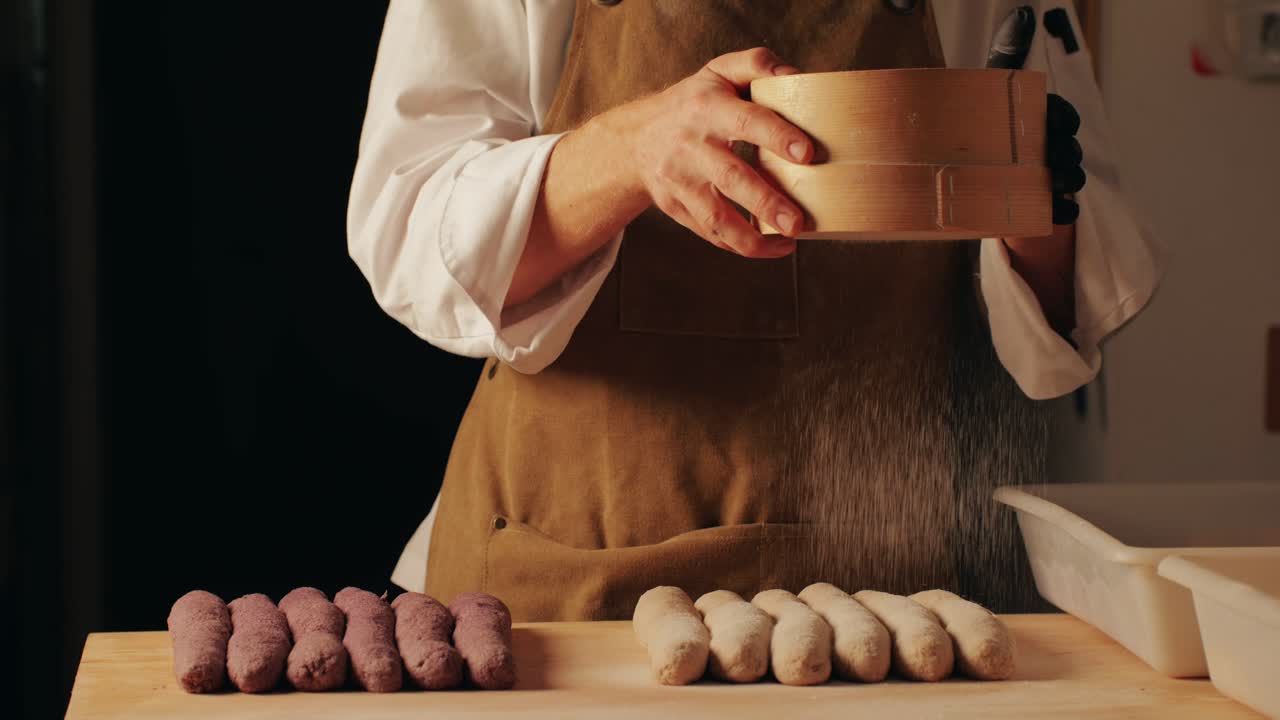 Bakery chef applying flour on dough, young man kneading dough, making bread using traditional recipe. Artisan bread is making by skill bakers using natural and high-quality ingredients. Food with health and flavour benefits.