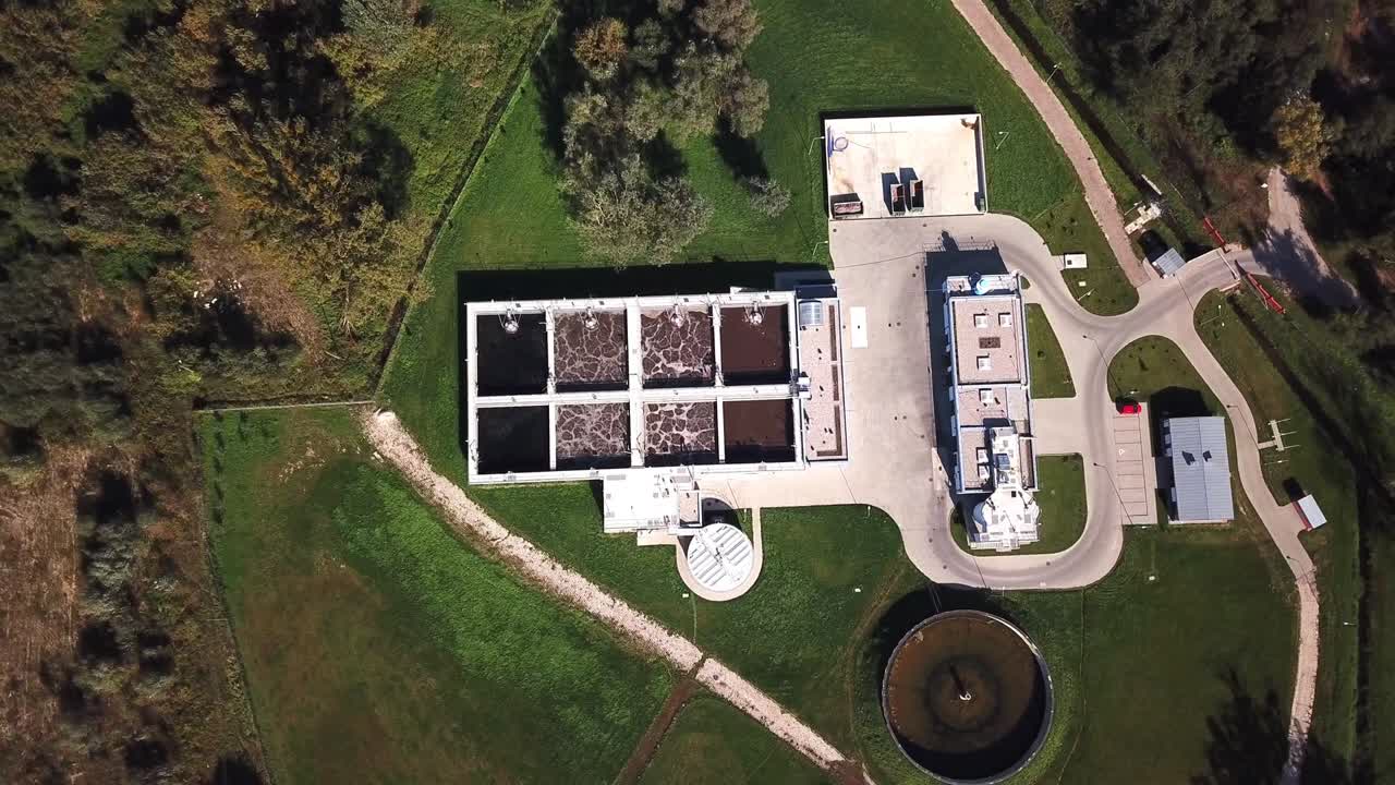 Luftaufnahme von oben: Flug über eine Kläranlage, auch bekannt als Abwasserbehandlungsanlage, die Verunreinigungen aus dem Abwasser entfernt, 4K