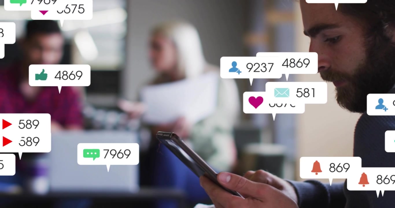Bearded man swiping tablet launching business notifications rising and fading, team collaborating