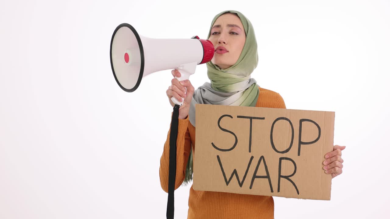 Wanita berhijab berunjuk rasa dengan megafon dan poster "Hentikan Perang"