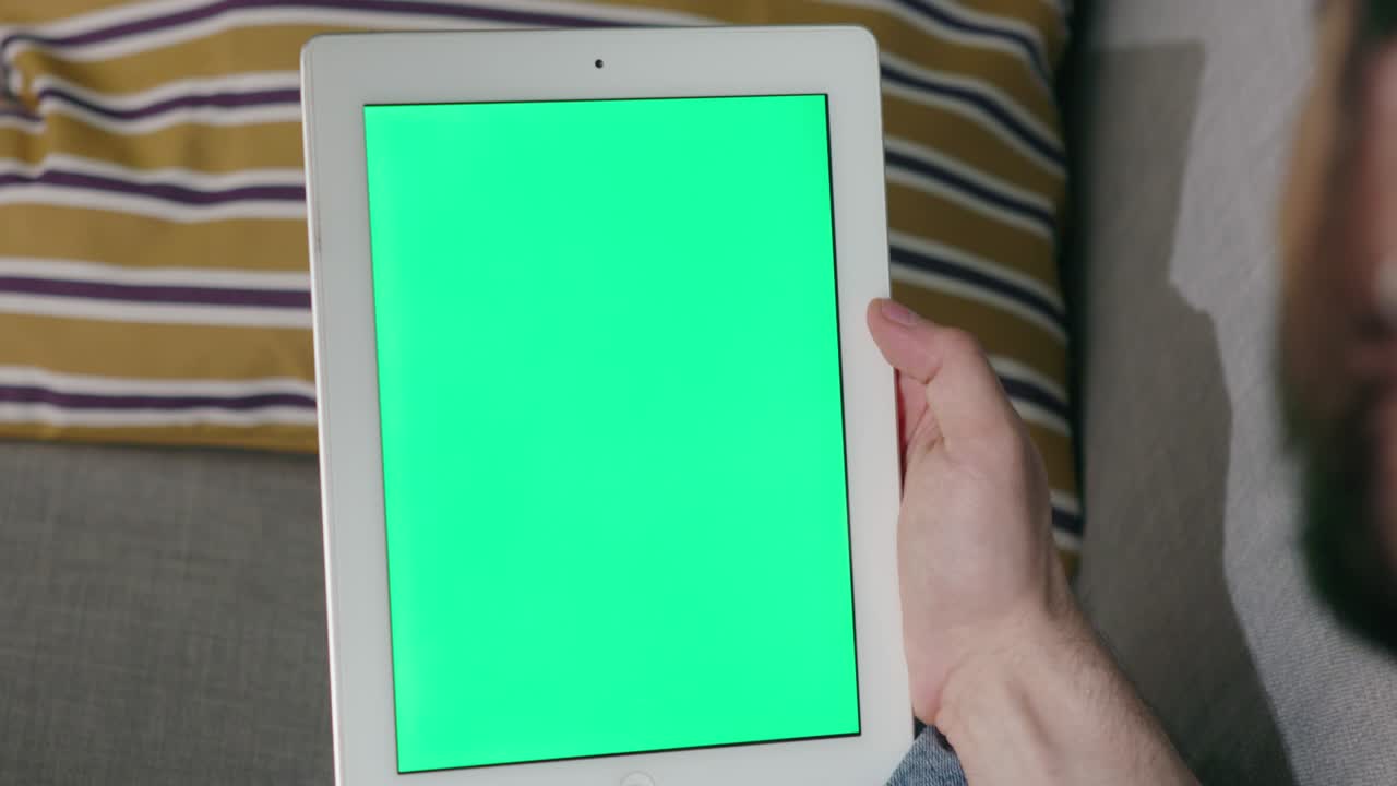 남자가 녹색 화면으로 태블릿 컴퓨터에 인사를 흔들고 있습니다.