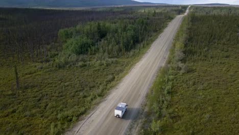 aerial view of adventure rv truck driving on a country road in spruce forest