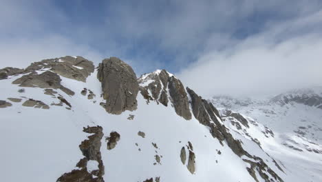 drone de carreras volando sobre montañas rocosas y nevadas, pirineos