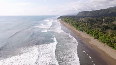 vista aérea de las olas del océano golpeando la costa en la playa dominical en costa rica, tiro de seguimiento