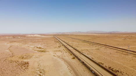 aerial view of a long straight highway stretching through a barren dessert on a sunny day
