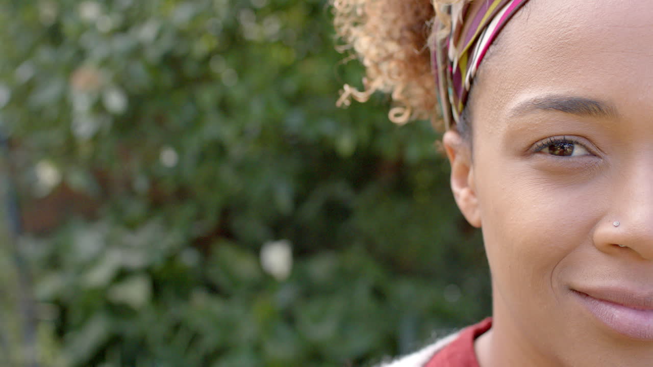 Ritratto di una felice donna afroamericana che sorride in giardino, spazio per la copia, slow motion