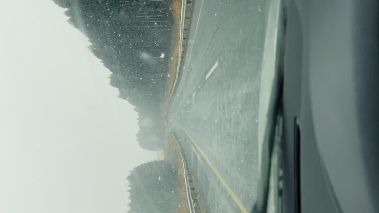 우울한 눈이 내리는 동안 우울한 자동차 운전자 숲 의 도로를 따라 와이퍼와 함께 앞 유리창을 청소합니다.