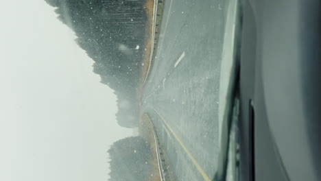 POV-Autofahrt-Bei-Nebligem-Starkem-Schneefall-Entlang-Der-Straße-Neben-Dem-Wald-Mit-Scheibenwischern,-Die-Die-Windschutzscheibe-Reinigen