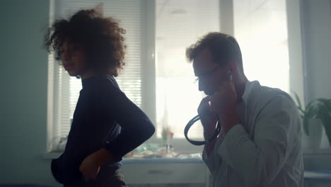 serious doctor listening breathing preteen patient using stethoscope in clinic