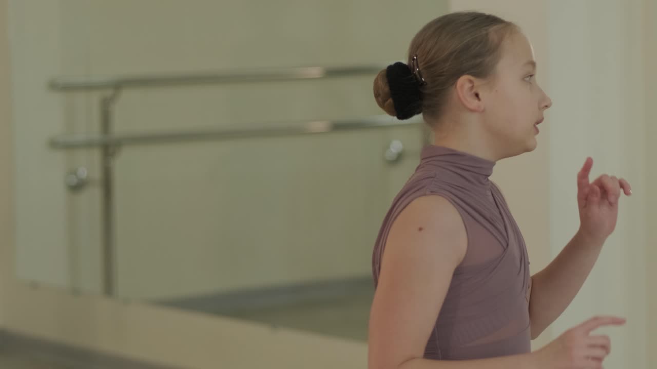un grupo de jóvenes estudiantes de ballet con ropa de baile negra practicando posiciones en un amplio estudio de ballet con pisos de madera y barras montadas en la pared. expresiones enfocadas y movimientos sincronizados.