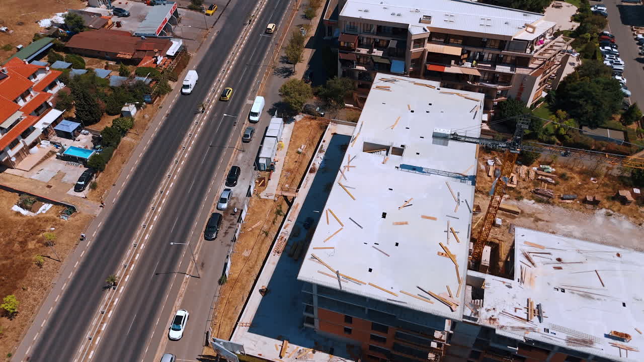 Varna, Bulgaria, 11 July 2025: New building site progress. Workers are busy at a building site with ongoing construction along a busy road under clear skies
