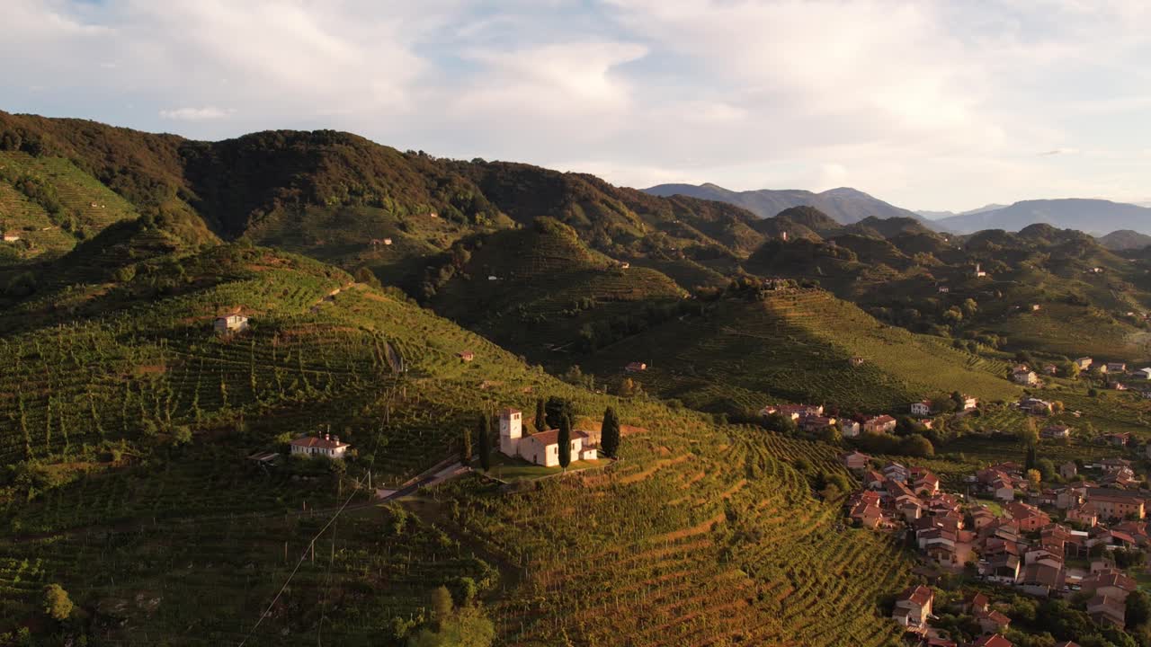Vista aerea del paesaggio sulle famose colline del Prosecco con filari di vigneti e una piccola chiesa, in Italia.