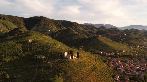 vista aérea del paisaje sobre las famosas colinas de prosecco con filas de viñedos y una pequeña iglesia, en italia
