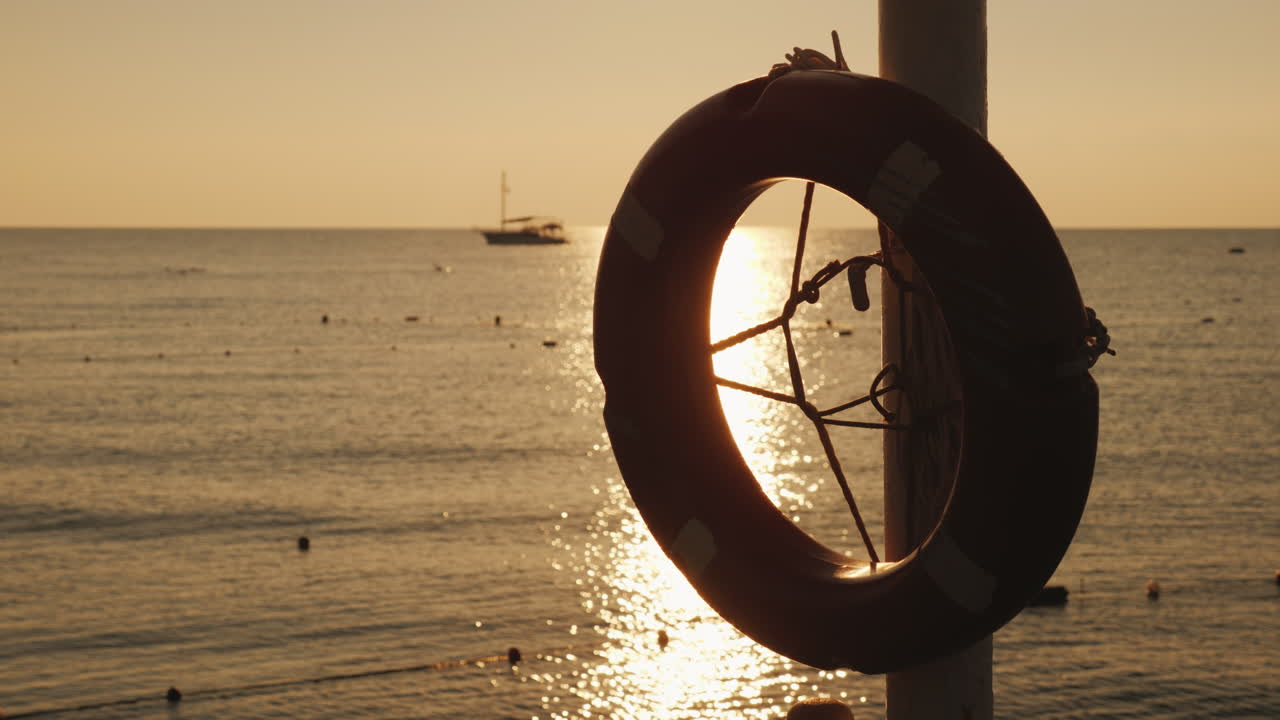전경에 있는 바다의 새벽이 멀리서 생명의 고리를 걸고 배가 보이는 경치 좋은 땅
