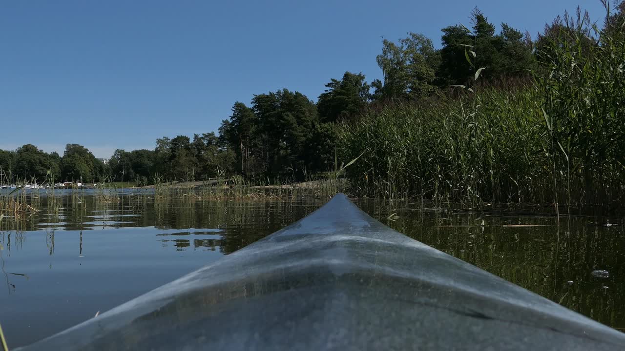 Kayaking slowly through reeds, kayak bow view, point of view