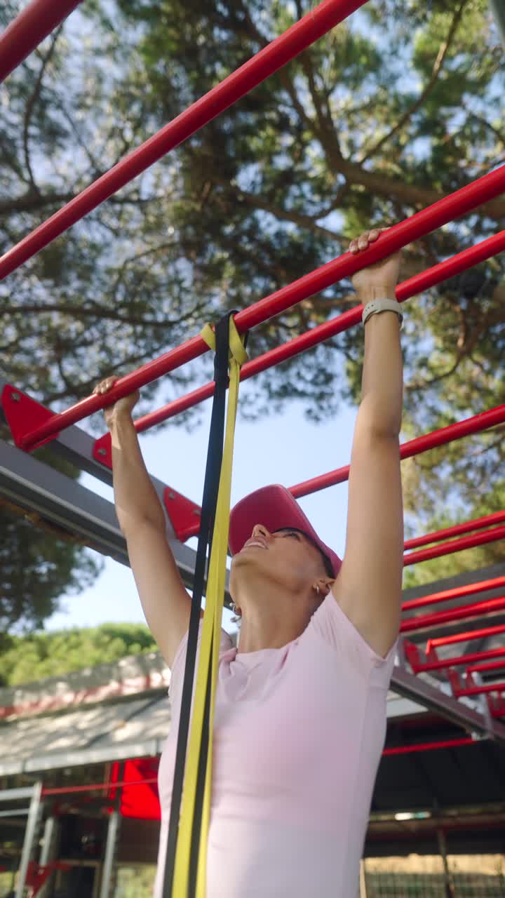 Woman Doing Pull-ups with Resistance Bands at Outdoor Gym