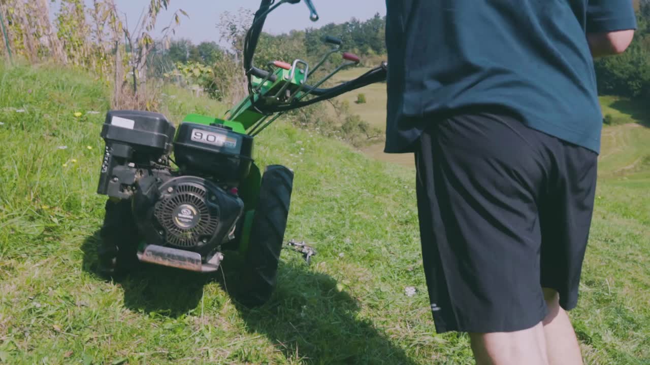 Mowing Fresh Green Grass In The Backyard With A Paddock Mower - close up, rear view