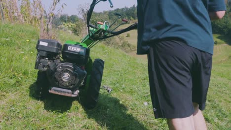 mowing fresh green grass in the backyard with a paddock mower - close up, rear view