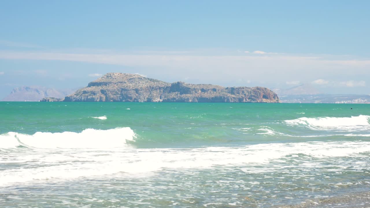 파도가 해변에 부딪치는 동안 아기오이 테오도로이(agioi theodoroi)라는 섬은 크레타 그리스에서 따뜻하고 유혹적으로 보이는 청록색 물을 배경으로 합니다.