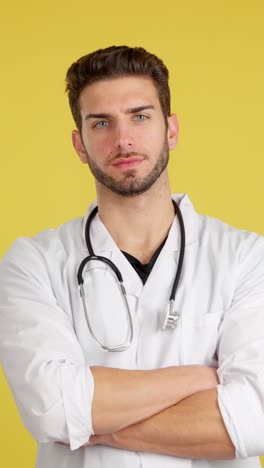 a serious male doctor in a white lab coat with a stethoscope against a yellow background