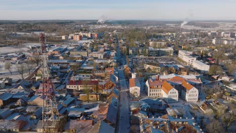 Aerial-establishing-view-of-Kuldiga-Old-Town-,-houses-with-red-roof-tiles,-sunny-winter-day,-travel-destination,-wide-drone-shot-moving-backward,-tilt-down