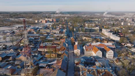 aerial establishing view of kuldiga old town , houses with red roof tiles, sunny winter day, travel destination, wide drone shot moving backward, tilt down