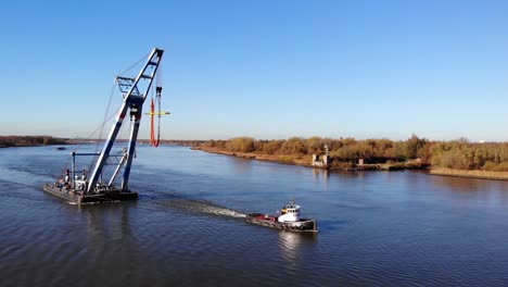 tugboat pulling the floating sheerleg with a large crane at inland water of barendrecht in netherlands