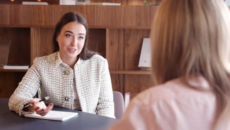 Businesswoman-Interviewing-Female-Candidate-At-Graduate-Recruitment-Assessment-Day-In-Office