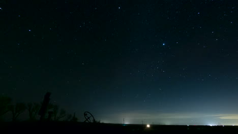la silueta del tractor oxidado marca el horizonte mientras las estrellas celestiales cruzan el cielo nocturno - lapso de tiempo