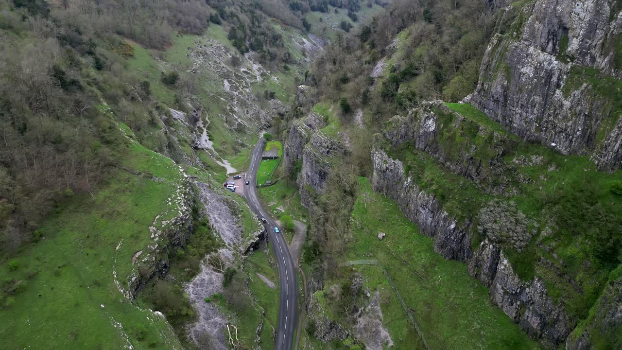 Aerial view of cars driving through Cheddar Gorge, surrounded by rugged cliffs.