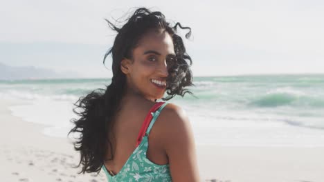 portrait oh happy hispanic woman standing in sun and wind on beach