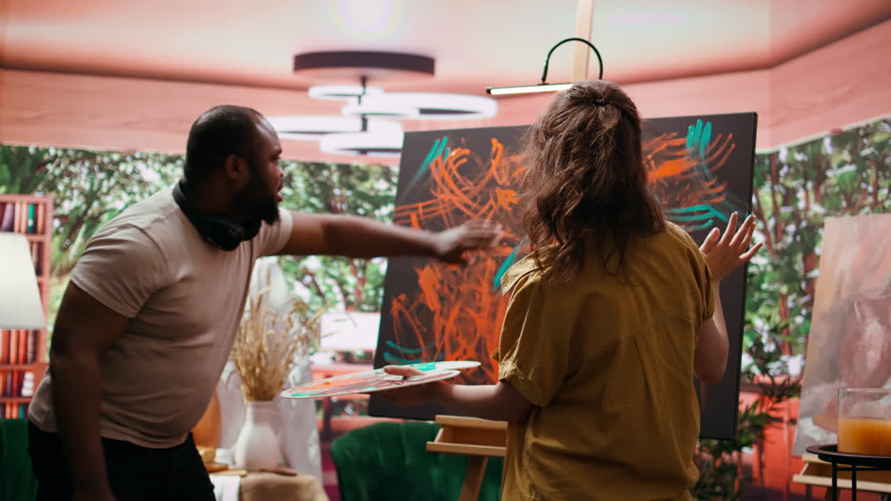 Artist painting in studio with a man